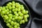 A branch of green juicy grapes in a plate. Black background. Top view