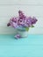 Branch of a lilac flower daylight on a blue wooden background, vase