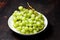 Branch of ripe green grape on plate with water drops. Juicy grapes on wooden background, closeup