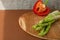 branches of fresh green asparagus on a wooden board, red big pepper on the background. brown background, top view. Basic