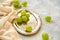 Branches of green grapes on silver vintage tray decorated with light brown cloth on gray concrete blurred background close up