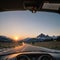 A brand new car is being driven on an empty countryside road at sunset with a be...