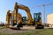 Brand new excavators parked on the roadside. Tower crane on background