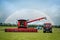 Brand new modern clean combine harvester and shiny red agricultural tractor rural farm field on summer day with rainbow in sky