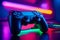 A brand-new PlayStation 5 controller set against a vibrant neon background