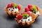Brandy snap baskets with ice cream and berries on black stone b