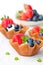 Brandy snaps baskets with soft cream cheese and berries on whit