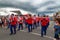 A brass band in red uniforms marching down the street