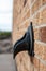 Brass metal down spout termination on the side of a brick building