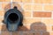 Brass metal down spout termination on the side of a brick building