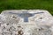 The brass plate used as a mounting point for a theodolite on top of a concrete British Ordnance Survey triangulation point, or Tri