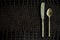 Brass utensil, knife and spoon, on synthetic crocodile black leather, used as background or texture