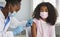 Brave African American teenage girl receives booster dose of coronavirus vaccine.