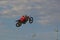 A brave biker jumps very high on a motorcycle and performs a stunt.