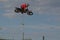 A brave biker jumps very high on a motorcycle and performs a stunt.