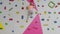 Brave child little blond girl is climbing up artificial wall in rock-climbing gym exercising.