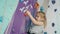 Brave child little girl climbing up artificial wall in modern rock-climbing gym