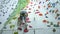 Brave child little girl is climbing up artificial wall in modern rock-climbing gym exercising alone using safety