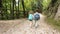 Brave children scouting in camping gear and holding hands walk along a forest gravel road in search of a route to a weekend family