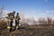 A brave firefighter puts out a grass fire in the villages close to the metropolis with the help of a water hydrant