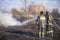 A brave firefighter puts out a grass fire in the villages close to the metropolis with the help of a water hydrant