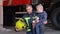 Brave firefighter in uniform holding little boy with a toy against the background of a fire engine