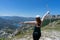 Brave girl conquering mountain peaks of mountains. Happy freedom hiker with hat and open arms Walking with wood stick, standing