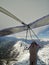 Brave hang glider pilots fly on high altitude over mountain ridge covered by snow