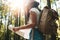 Brave hipster girl traveling alone and looking around in forest on outdoors wearing treveler backpack and hold location map in han