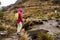 A brave lonely female hiker crossing a wooden bridge in the Cajas National Park in the highlands of Ecuador in a rainy day