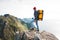 Brave man tourist with backpack standing on the edge mountain above sea and looking forward away