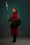 Brave woman warrior with weapon posing in studio.