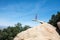 Brave young adult woman hiker stands on top of Potato Chip Rock in San Diego California