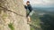 A brave young man alone climbs a high rock without insurance.