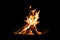 Brazier or fire bowl with burning wood logs in front of black ba