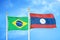 Brazil and Laos two flags on flagpoles and blue cloudy sky