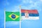 Brazil and Serbia two flags on flagpoles and blue cloudy sky