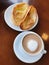 Brazilian breakfast.  Capuccino cup and toasted bread with butter background