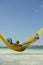 Brazilian Man Relaxing in Beach Hammock with Drinking Coconut