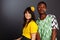 Brazilian and Nigeria fan couple in soccer uniform celebrate on gray background