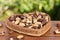 Brazilian nut, known as `Castanha do ParÃ¡` in a heart-shaped basket on a wooden table with an unfocused garden background.