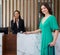 A Brazilian tourist in green clothes drag her luggage to the check-in point. The airline staff smiled while answering the phone