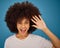 Brazilian woman, afro or surprise face on blue background in studio in waving, hi or greeting hand gesture. Portrait