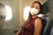 Brazilian woman with protective face mask sleeping relaxed on airplane flight during pandemic coronavirus