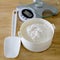 Bread flour in white bowl with rubber scraper and scale on wood