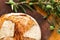 Bread loaf on a wooden board with green olives on branch with leaves over a used oak wood background