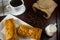 Bread pie on white plate and black coffee with milk, coffee beans in cloth bag