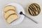 Bread in plate, canned sprats in metallic jar, fork