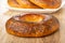 Bread rings with poppy in white plate on background, single baranka on table