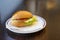 Bread roll bun with cheese, tomato and lettuce served as breakfast or fast snack on a plate on a dark wooden table, copy space